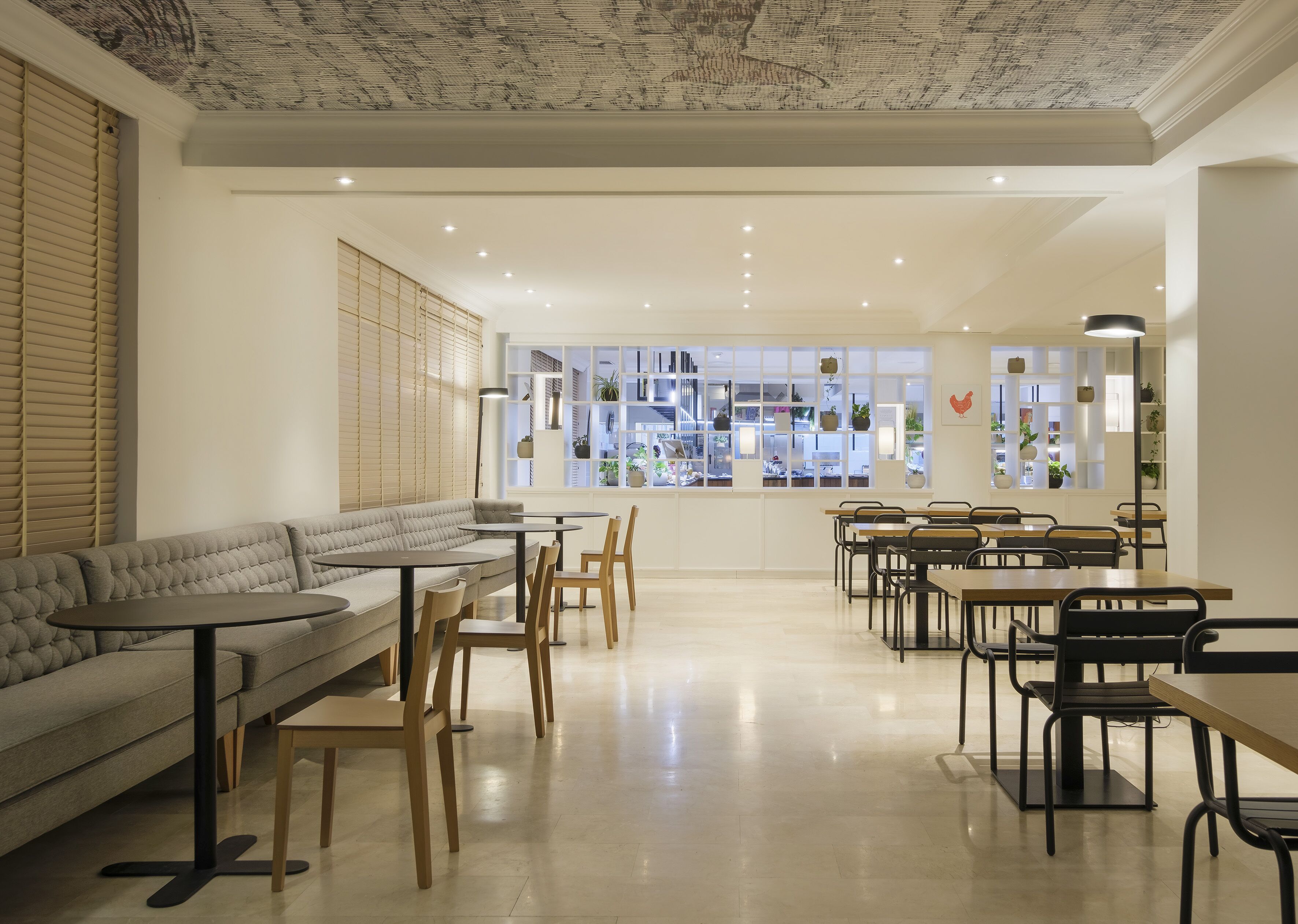 A modern cafe with a sofa, tables, and chairs arranged for seating.