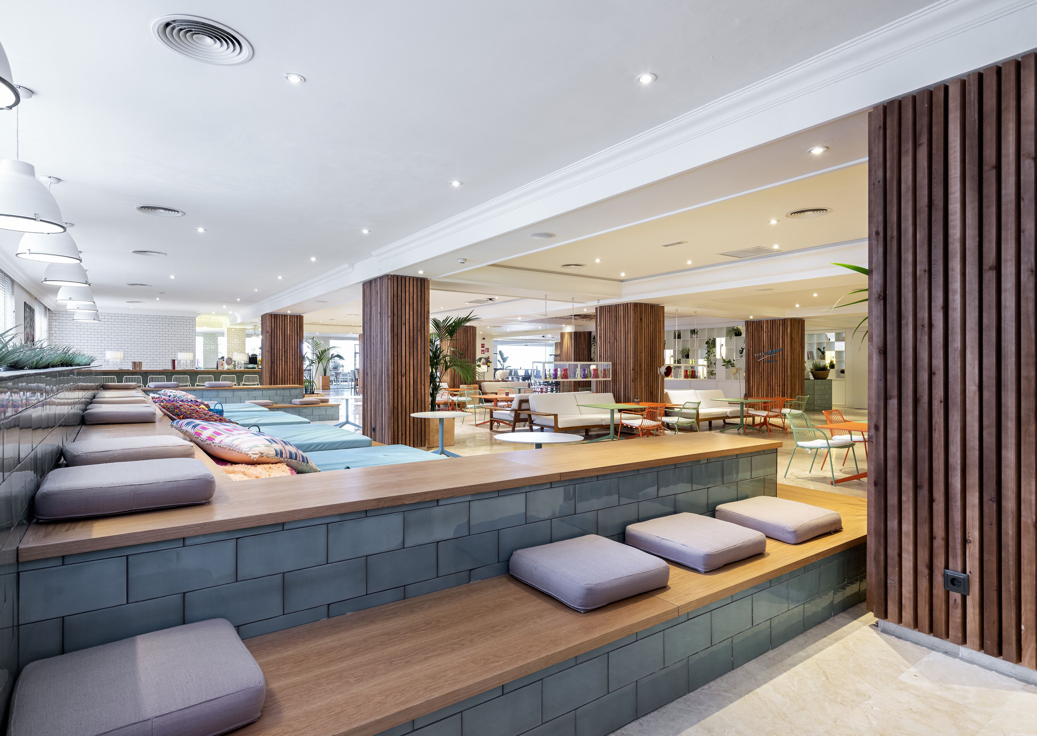 A modern indoor space with seating areas, a pool, and a kitchen area.