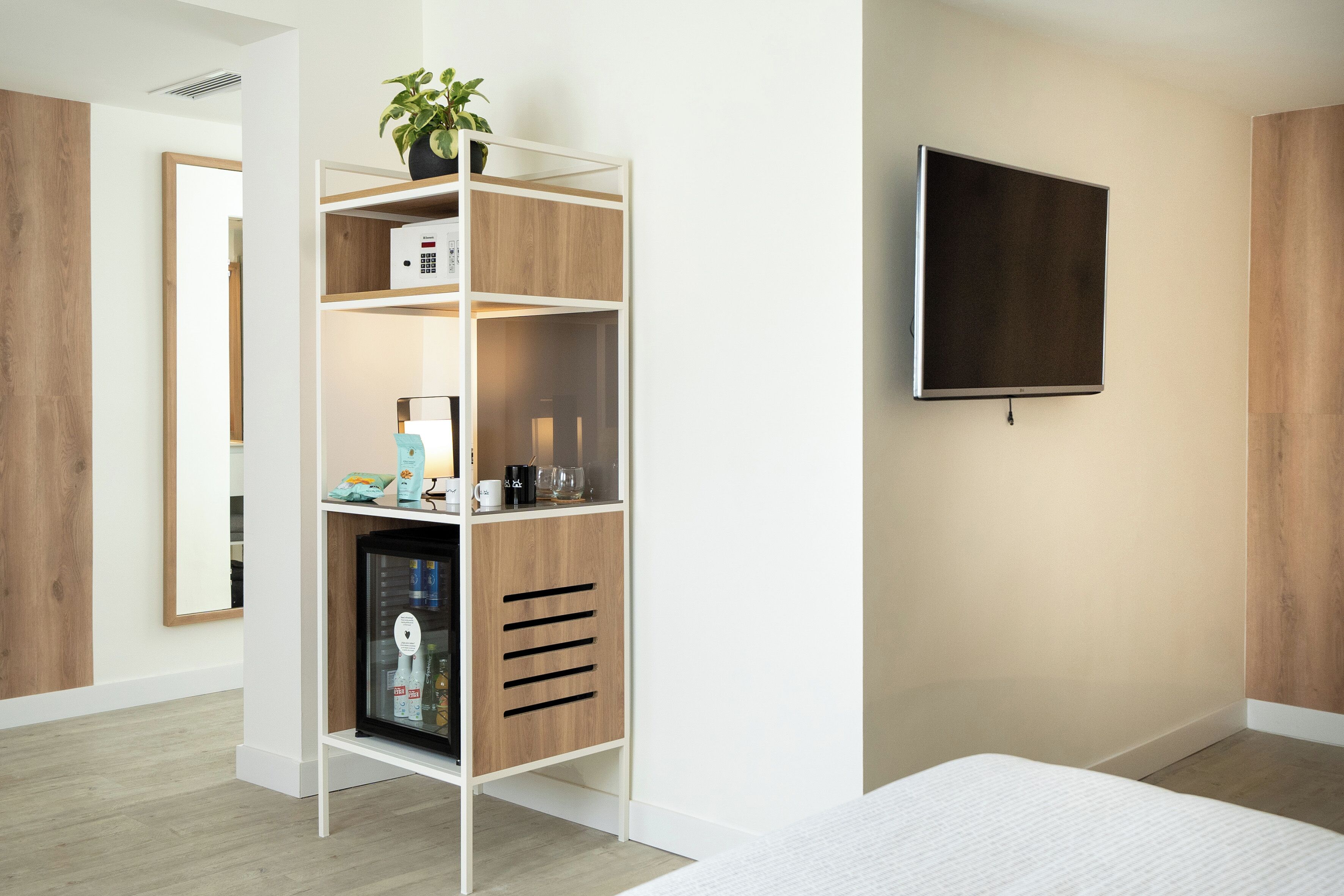 A modern bedroom with a built-in wardrobe, a television mounted on the wall, and a bedside table.