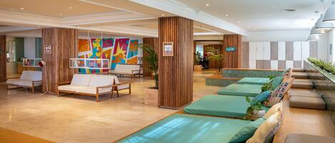A lobby with seating areas, wooden columns, and a colorful mural.