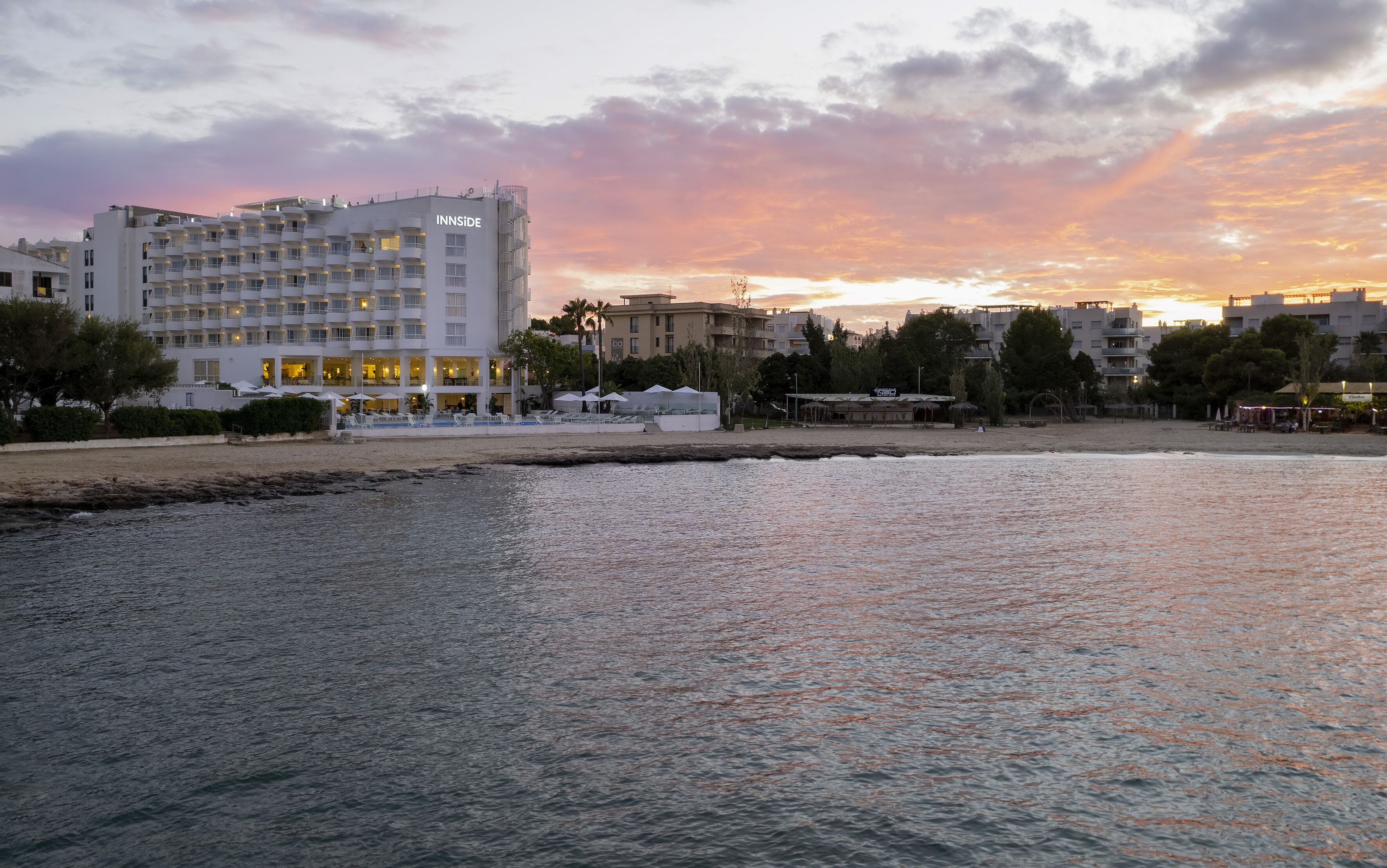 Un hotel frente al mar con varios balcones, una zona de piscina y vistas a la playa.