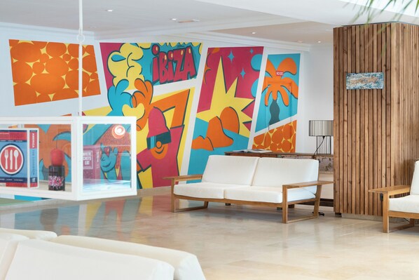 A modern lobby with colorful murals, a white sofa, and wooden accents.