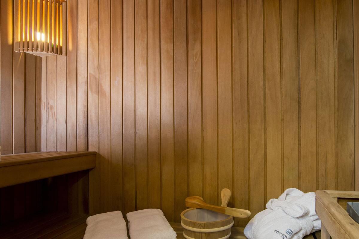 Uma sauna de madeira com bancos, aquecedor para bancos e toalhas.