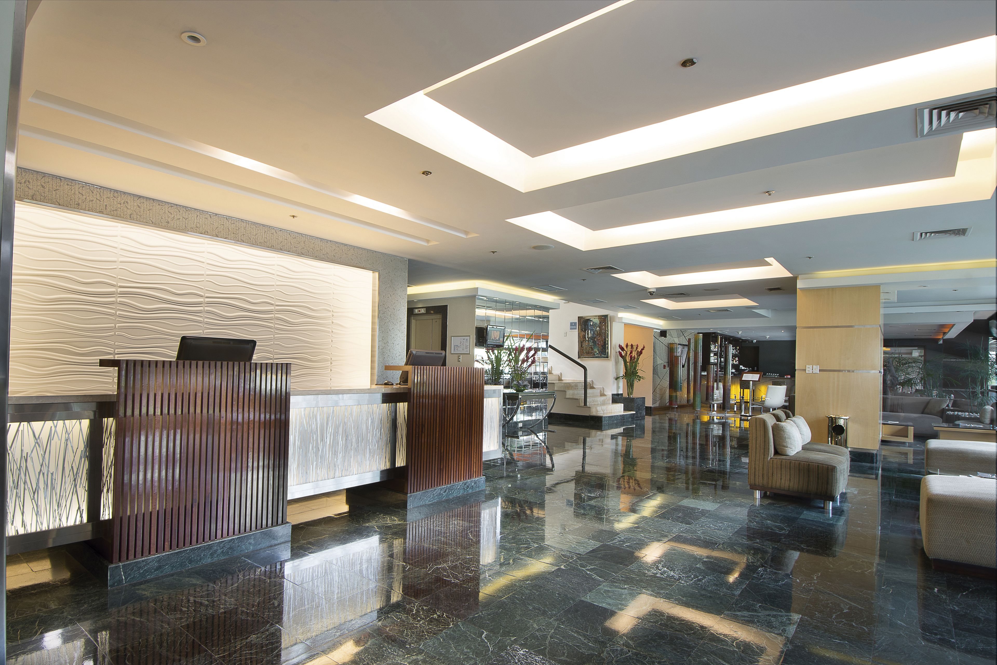 Eine moderne Lobby mit einer Rezeption, einer Sitzecke und einer Treppe zu den oberen Stockwerken.