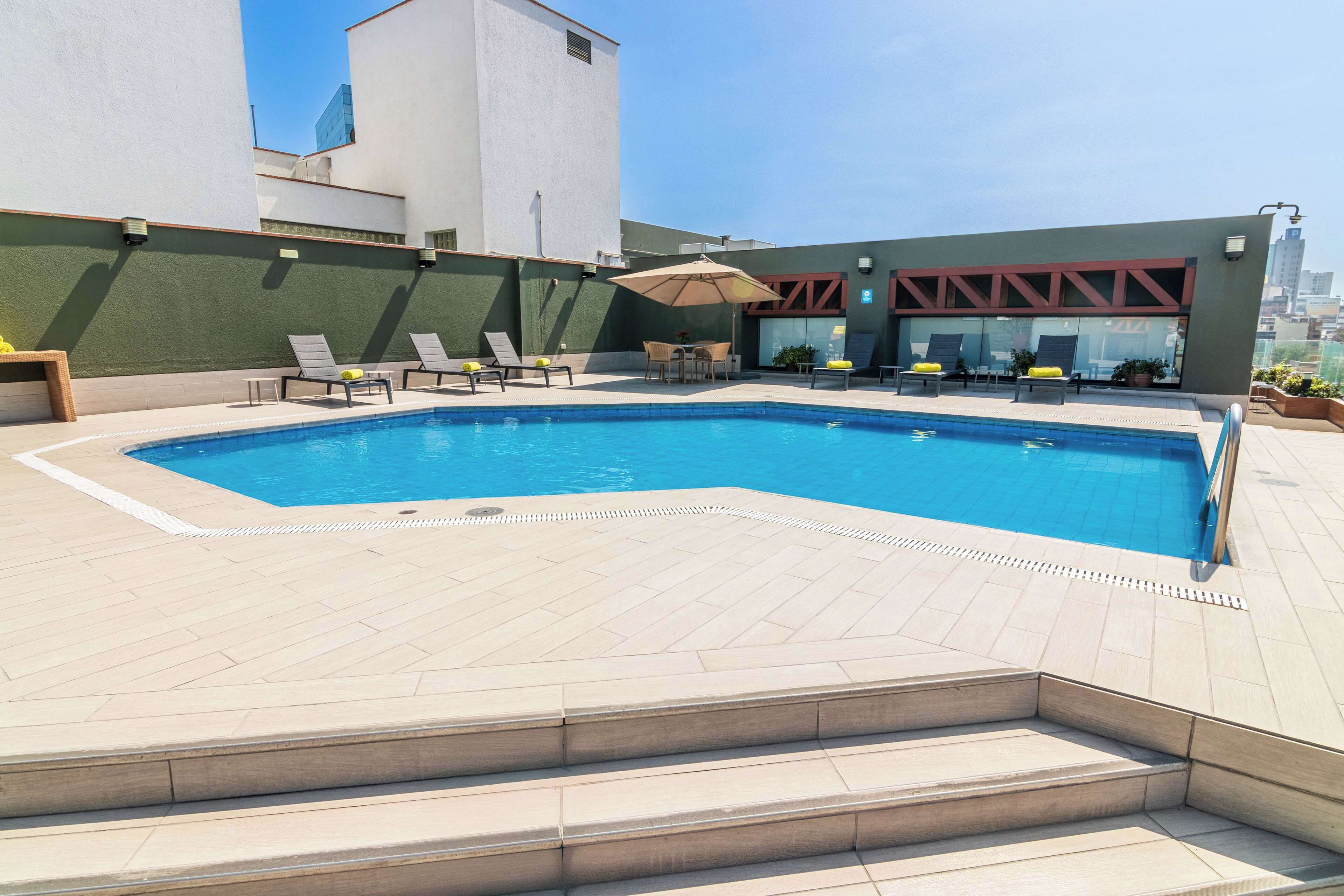 Una piscina al aire libre, sombrillas, sillones reclinables de piscina