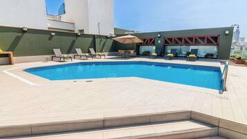 Una piscina al aire libre, sombrillas, sillones reclinables de piscina