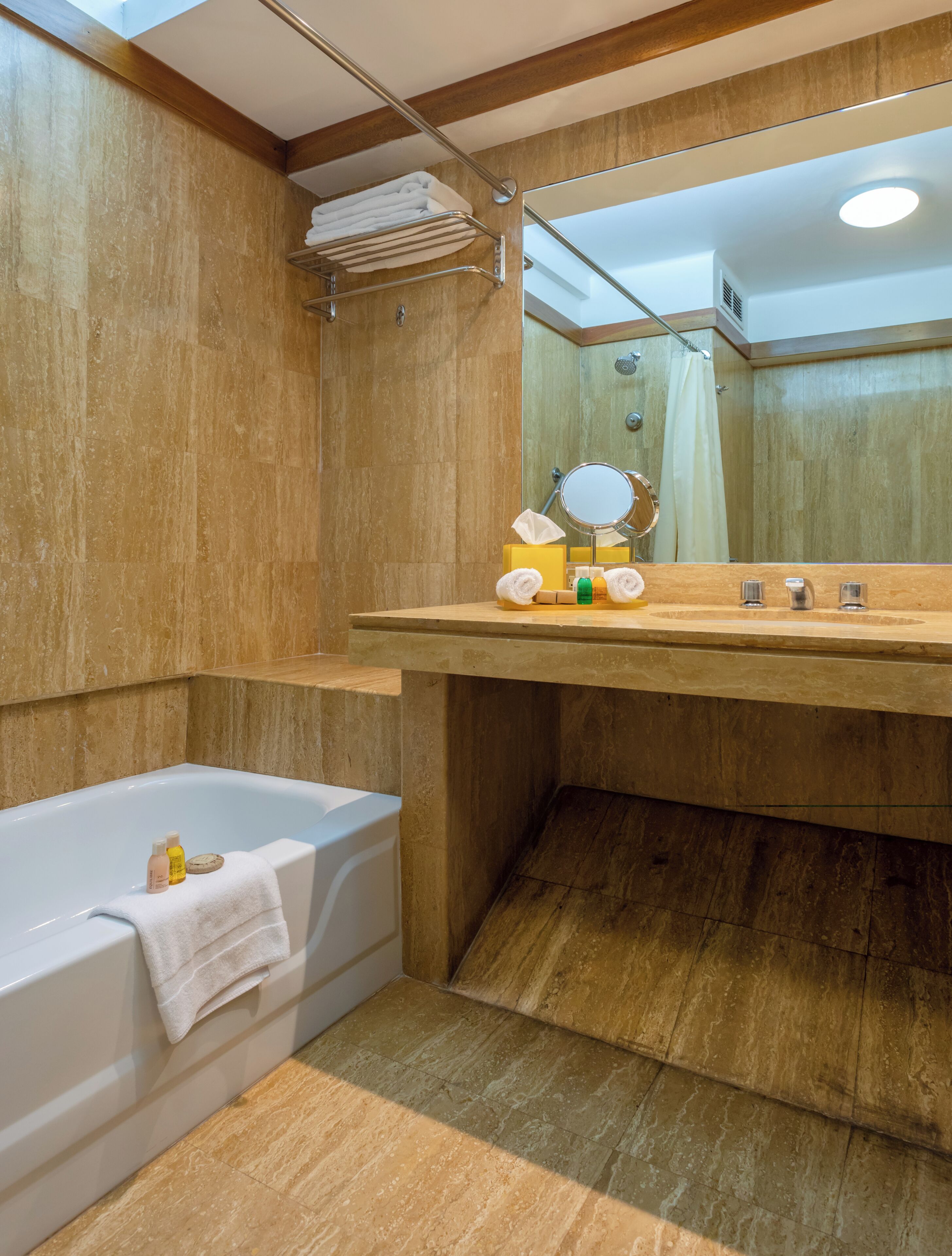 Un baño con tocador de madera, bañera y espejo.