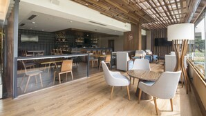 Un interior moderno con suelo de madera, zona de bar y diferentes distribuciones de asientos.
