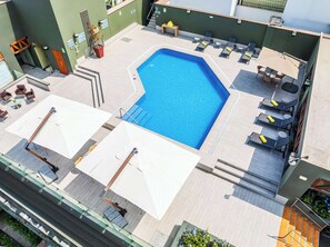 A rooftop swimming pool with sun loungers and umbrellas, surrounded by a tiled deck and a green wall. - Sonesta Hotel El Olivar Lima (Lima)