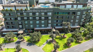 Un hotel moderno con varios pisos, balcones y un jardín bien cuidado.