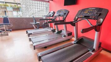 A gym with treadmills, exercise bikes, and a red wall.