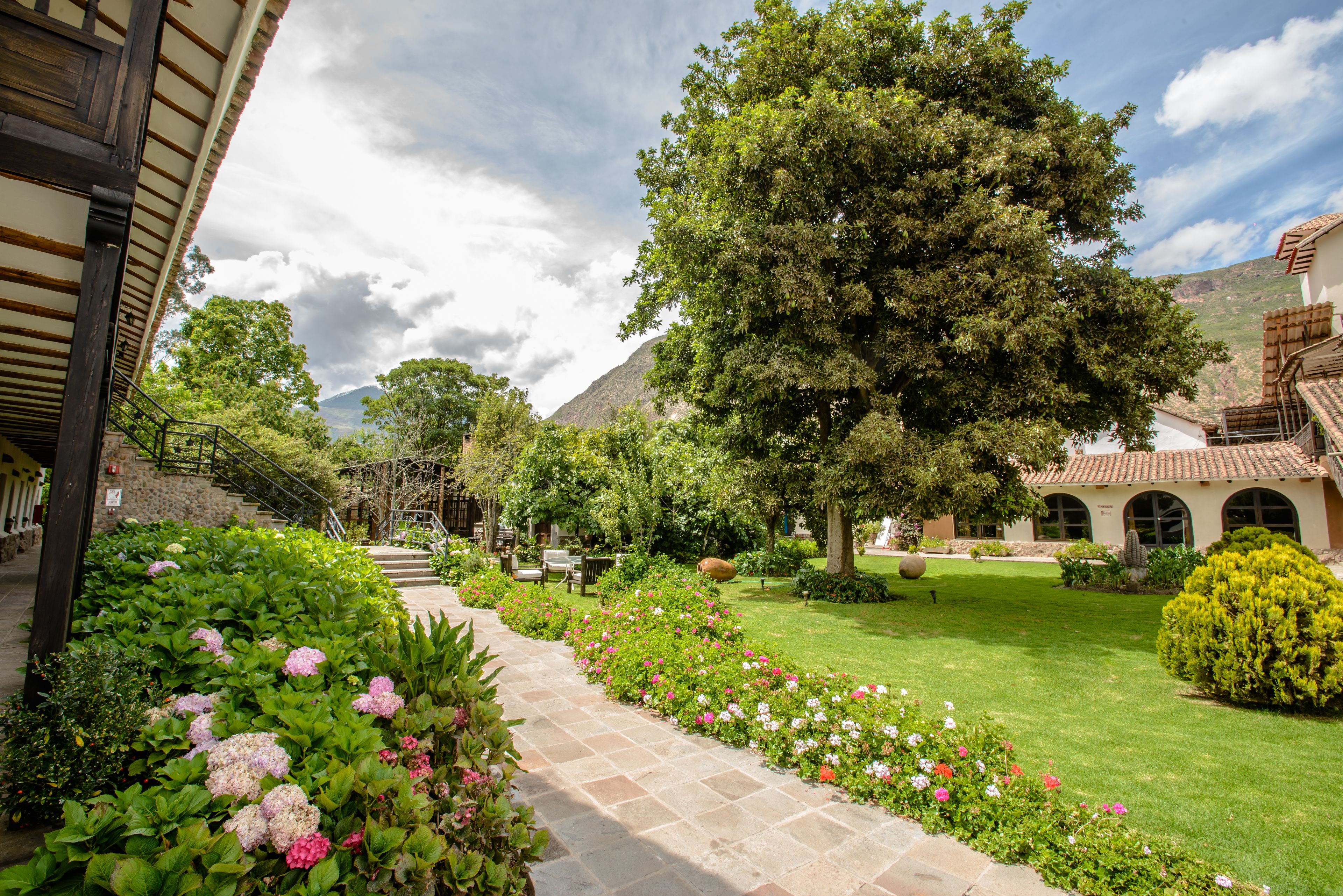 Un sendero en un jardín que lleva a un edificio con fachada de piedra y ventanas arqueadas.