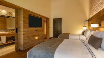 Habitación de hotel con una cama grande, un panel de pared de madera, un televisor, un baño con salpicadero de azulejos estampados y una mesita de noche.