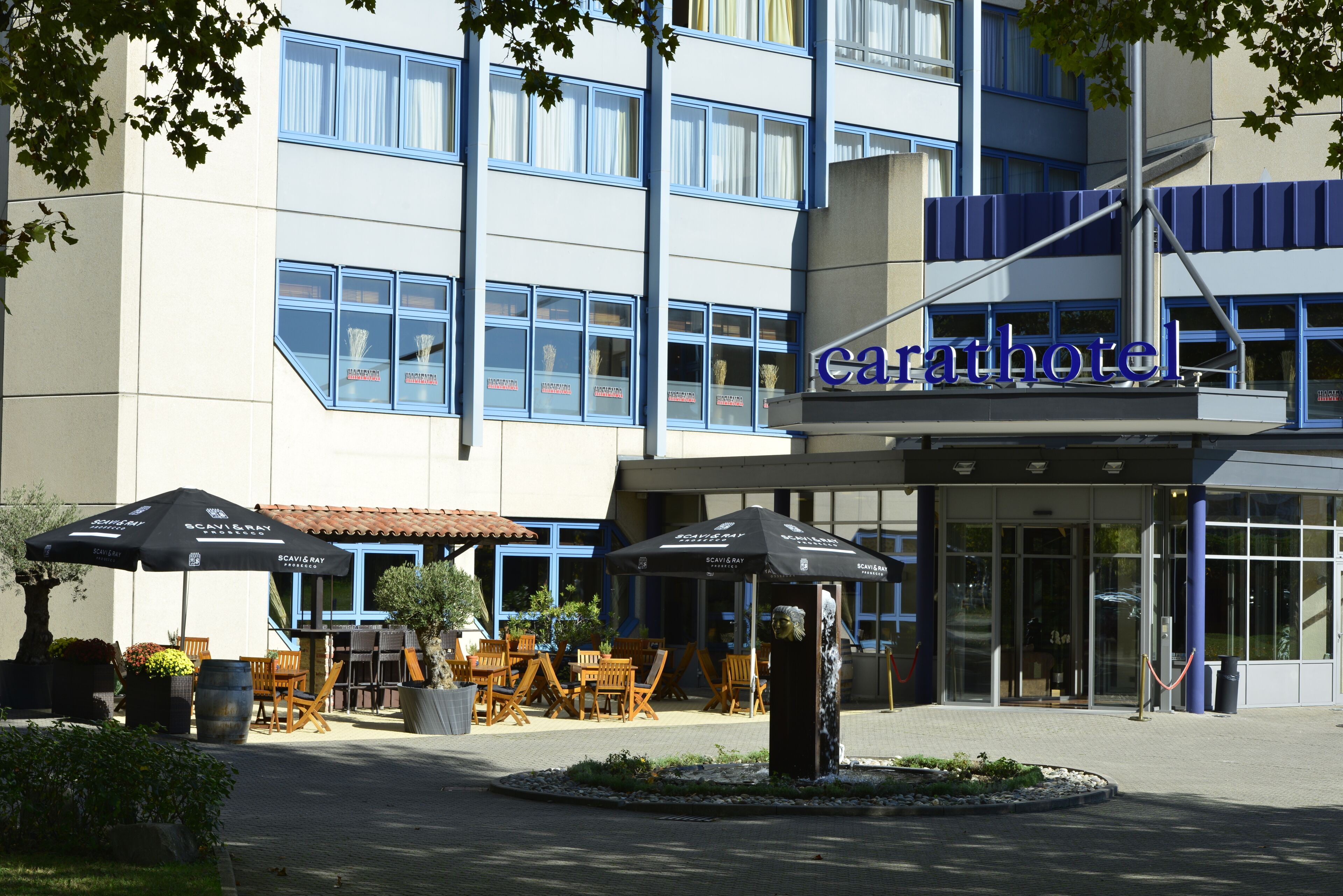 Un hotel con posti a sedere all'aperto, una fontana centrale e un ingresso ben visibile.