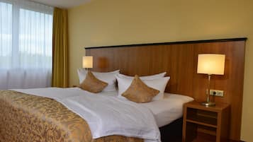 Ein Hotelzimmer mit einem großen Bett, zwei Nachttischlampen und einem hölzernen Kopfteil.
