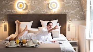 Een hotelkamer met een groot bed, twee wandlampen, een nachtkastje met een ontbijttafel en een raam met luxaflex.
