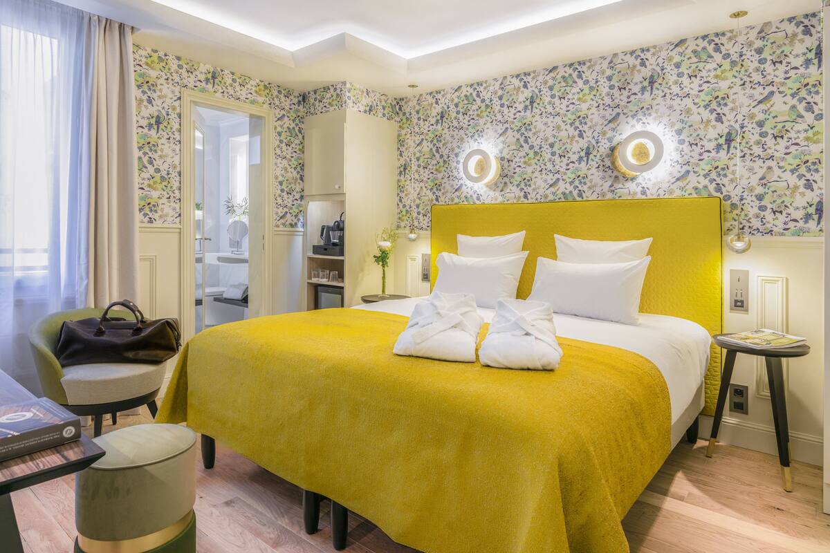 Een hotelkamer met een groot bed, een nachtkastje, een stoel en een kleine tafel met een boek.