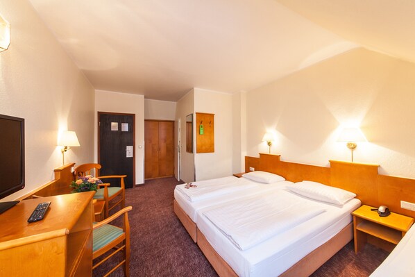 A hotel room with two beds, a desk with a chair, a TV, and two bedside lamps. - Hotel Ahl Meerkatzen (Cologne)