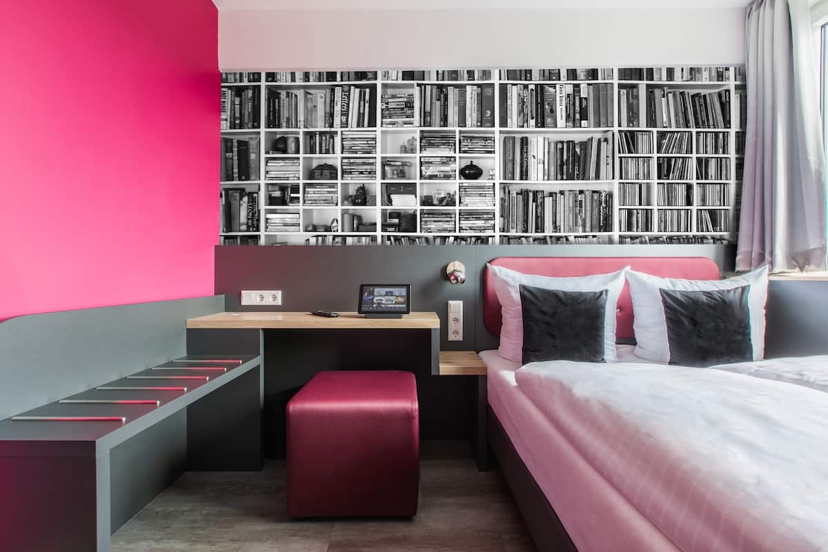 A modern bedroom with a large bookshelf, a desk, and a comfortable bed.