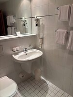 A bathroom with a sink, mirror, towel rack, and a hairdryer.