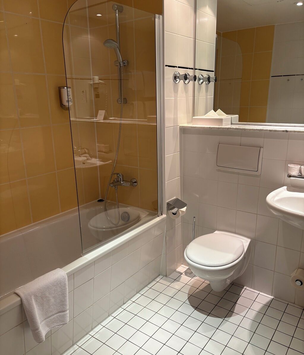 A bathroom with a glass-enclosed shower, a toilet, and a sink.