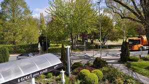 A hotel entrance with a covered walkway, a sign indicating a pedestrian crossing, and a road with a truck. - Hotel Am Wall Soest (Soest)