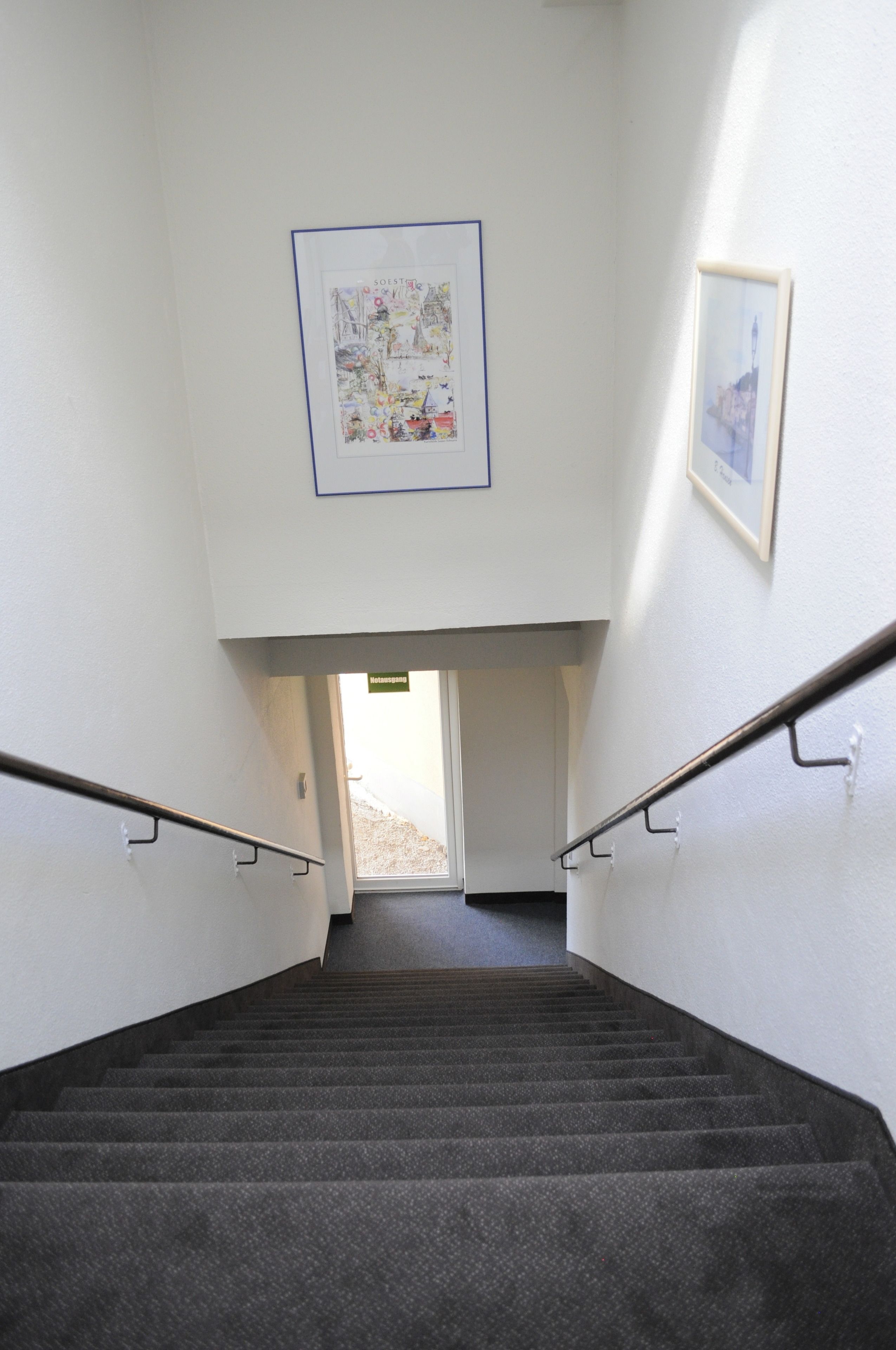 A staircase with a framed picture on the wall, a handrail, and a door at the top.