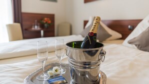 A bed with a metal tray holding a bottle of champagne, two glasses, and a small card. - Hotel Am Wall Soest (Soest)