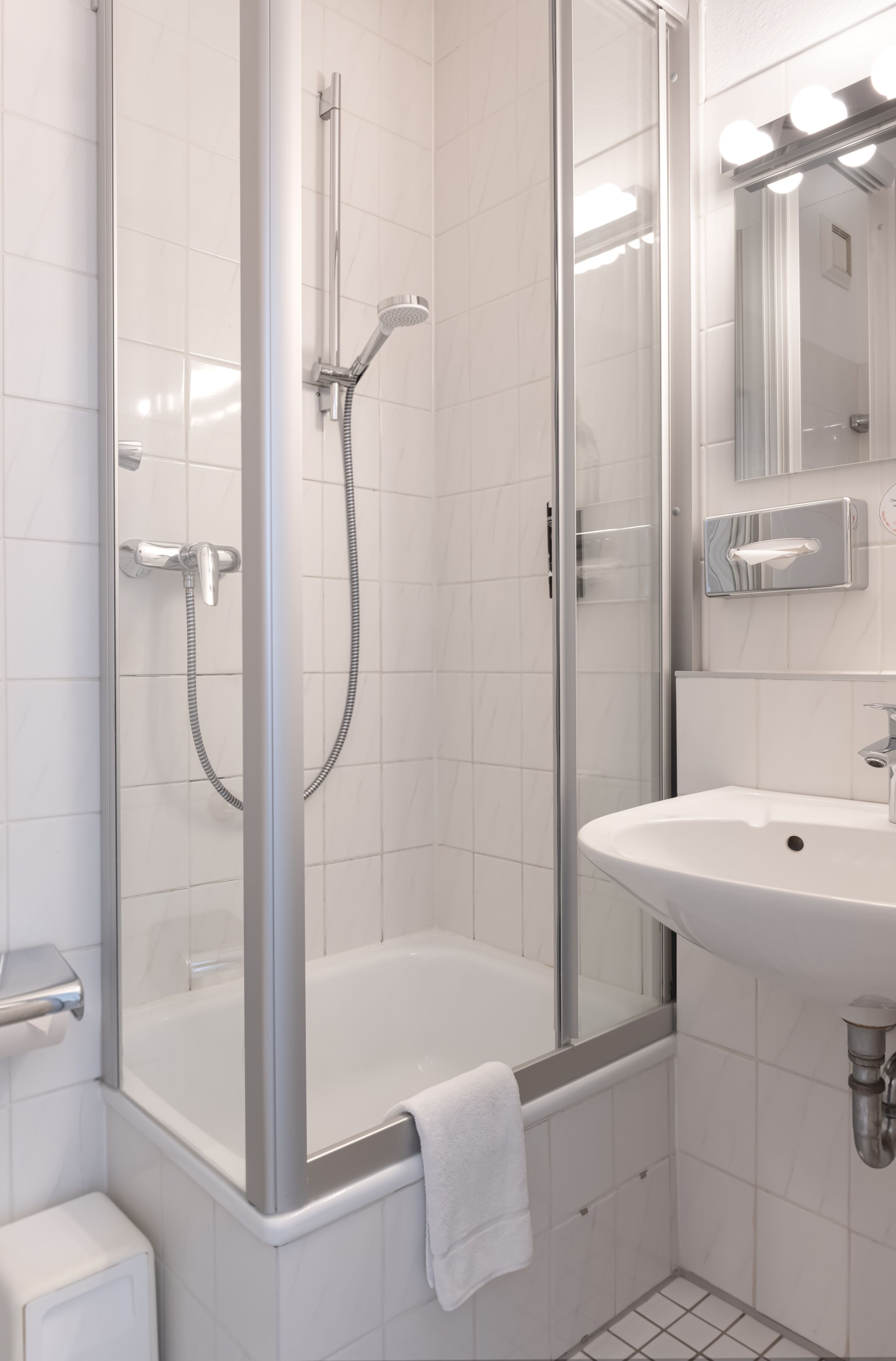 Un baño moderno con cabina de ducha de vidrio, un lavabo blanco y un espejo.