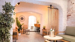 A cozy interior with a rustic stone wall, a wooden table with a candle holder, and several potted plants.