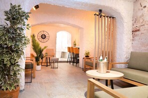 Experience a warm and inviting space with a high, arched ceiling, exposed brickwork, and a cozy seating area.