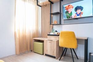 Una camera moderna con una scrivania in legno, una sedia gialla, una TV a parete e una finestra con tende.