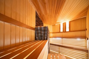Relax in a serene sauna room with benches along the walls and a stone backdrop.