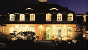 A large, illuminated building with multiple windows and a prominent entrance. - Hotel Am Stadtpark (Hilden)
