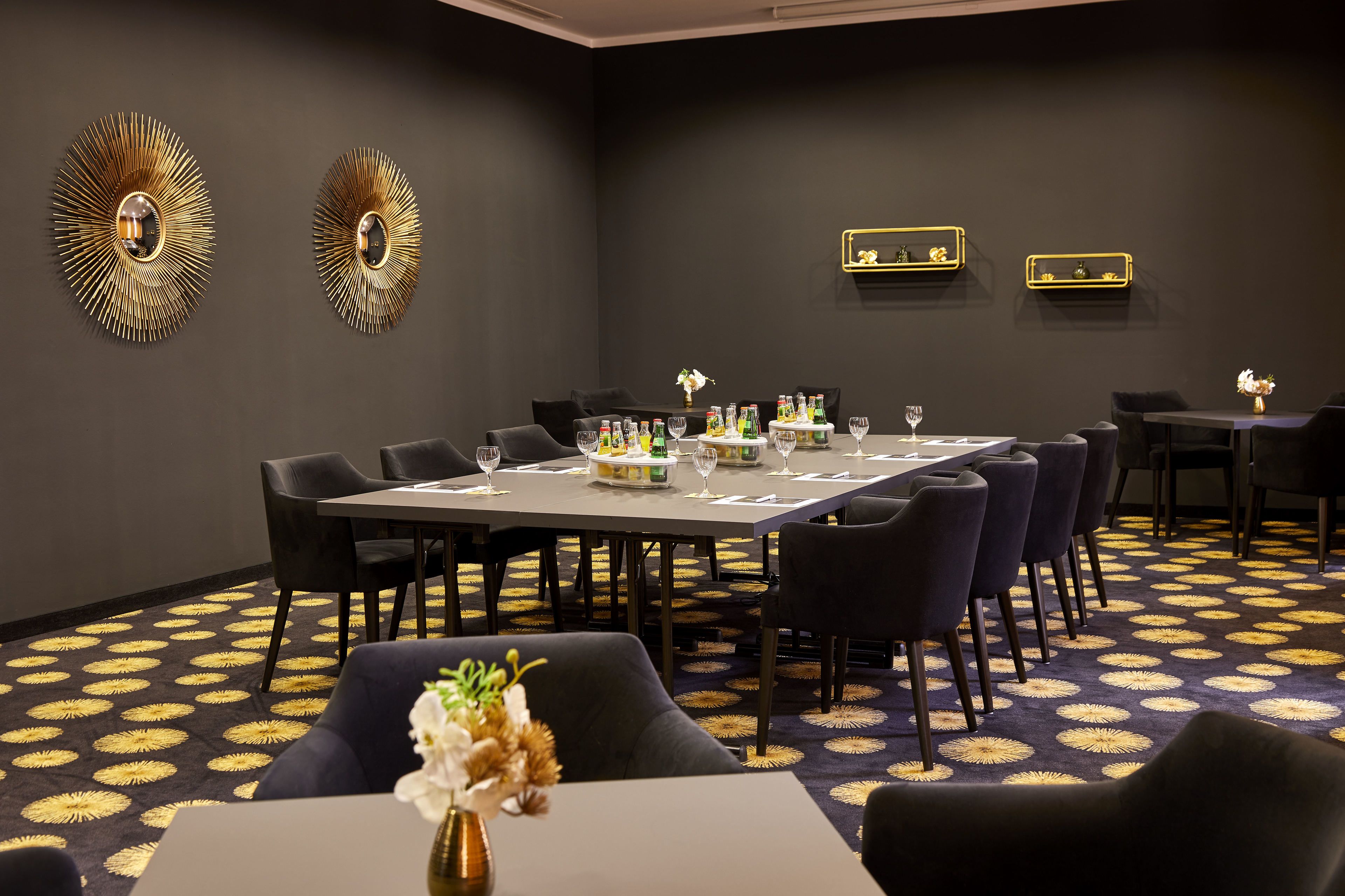 A conference room with a long table, chairs, and a patterned carpet.