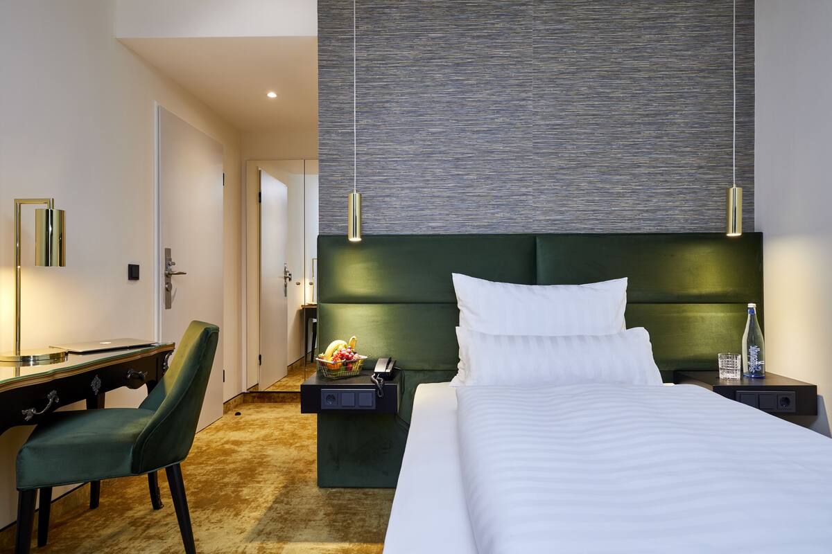 Ein Hotelzimmer mit einem Bett, einem Schreibtisch, einem Stuhl, einem Nachttisch und einer Wandleuchte.