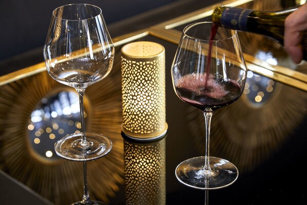 A table with two wine glasses and a bottle of red wine being poured into one of them. - Das Carls Hotel (Düsseldorf)