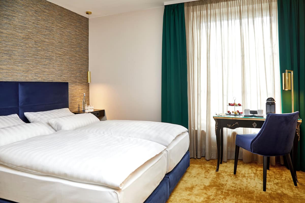Ein Hotelzimmer mit einem großen Bett, einem Schreibtisch mit Stuhl und einem Fenster mit Vorhängen.