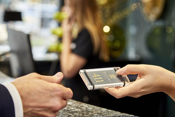 A person holding a compact device labeled 'DAS CARLS 411' with a transparent case. - Das Carls Hotel (Düsseldorf)