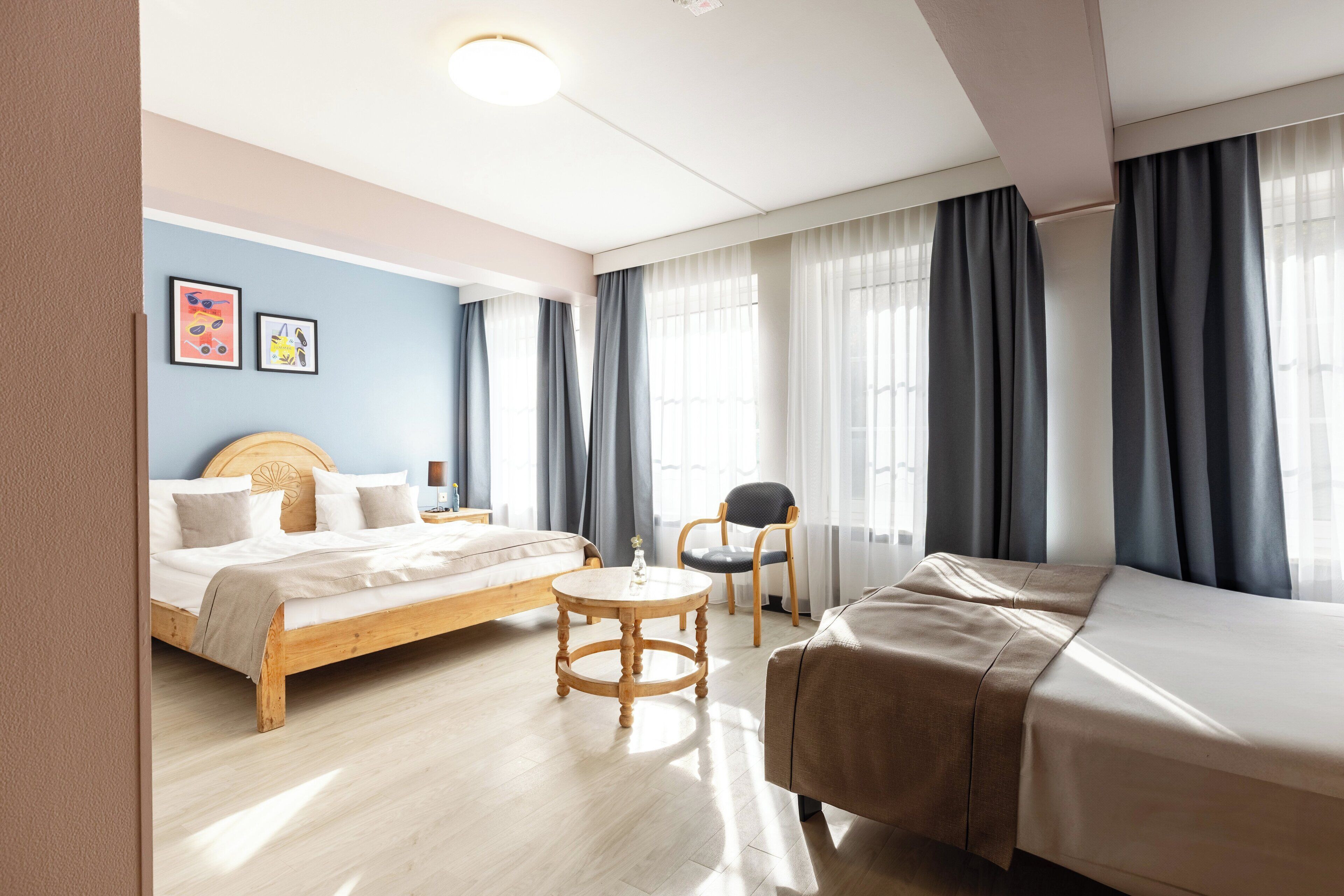 Una habitación de hotel con una cama de madera, una mesa redonda de madera, una silla y un sofá.