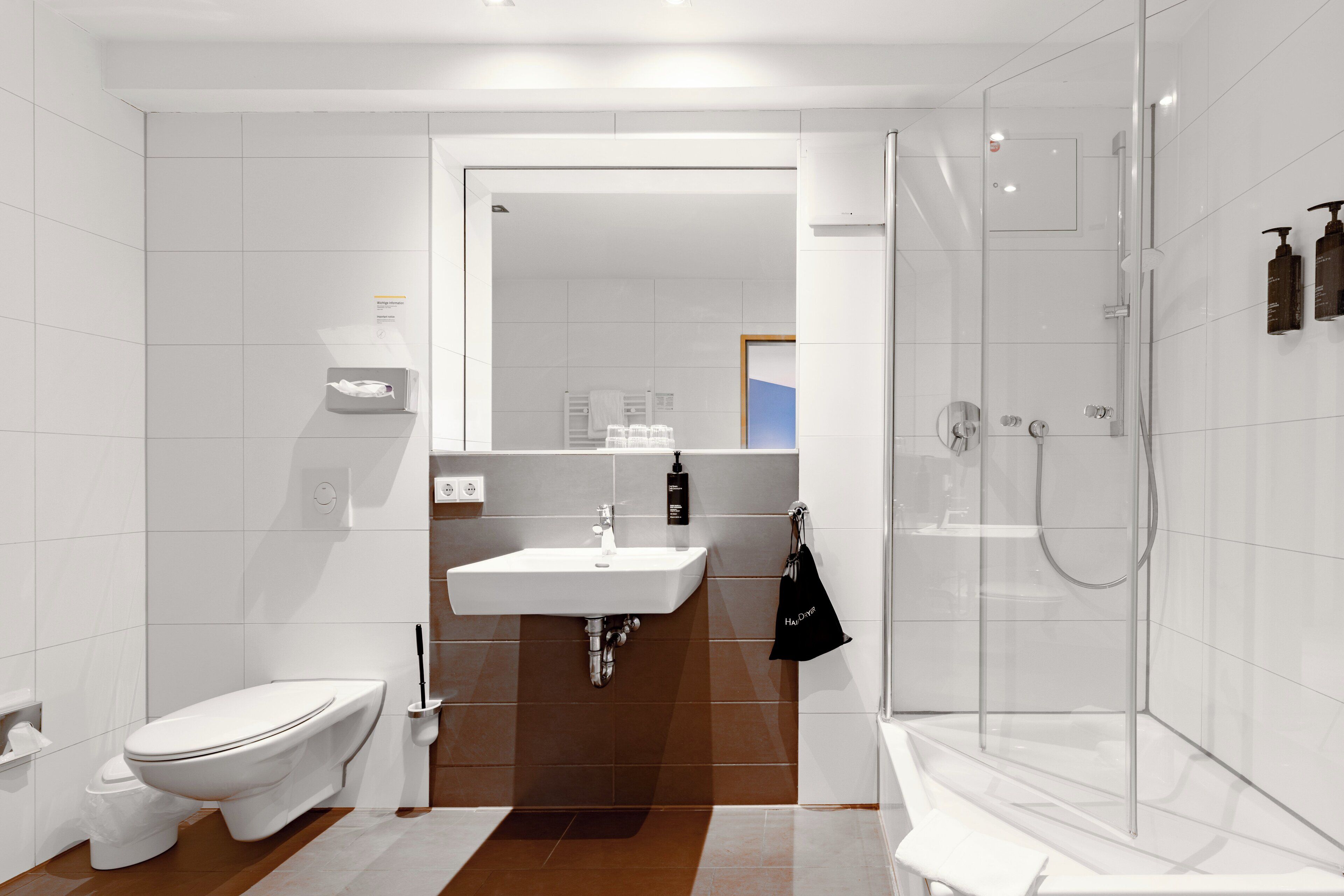 Une salle de bain moderne équipée de toilettes, d’un lavabo et d’une douche à parois de verre.