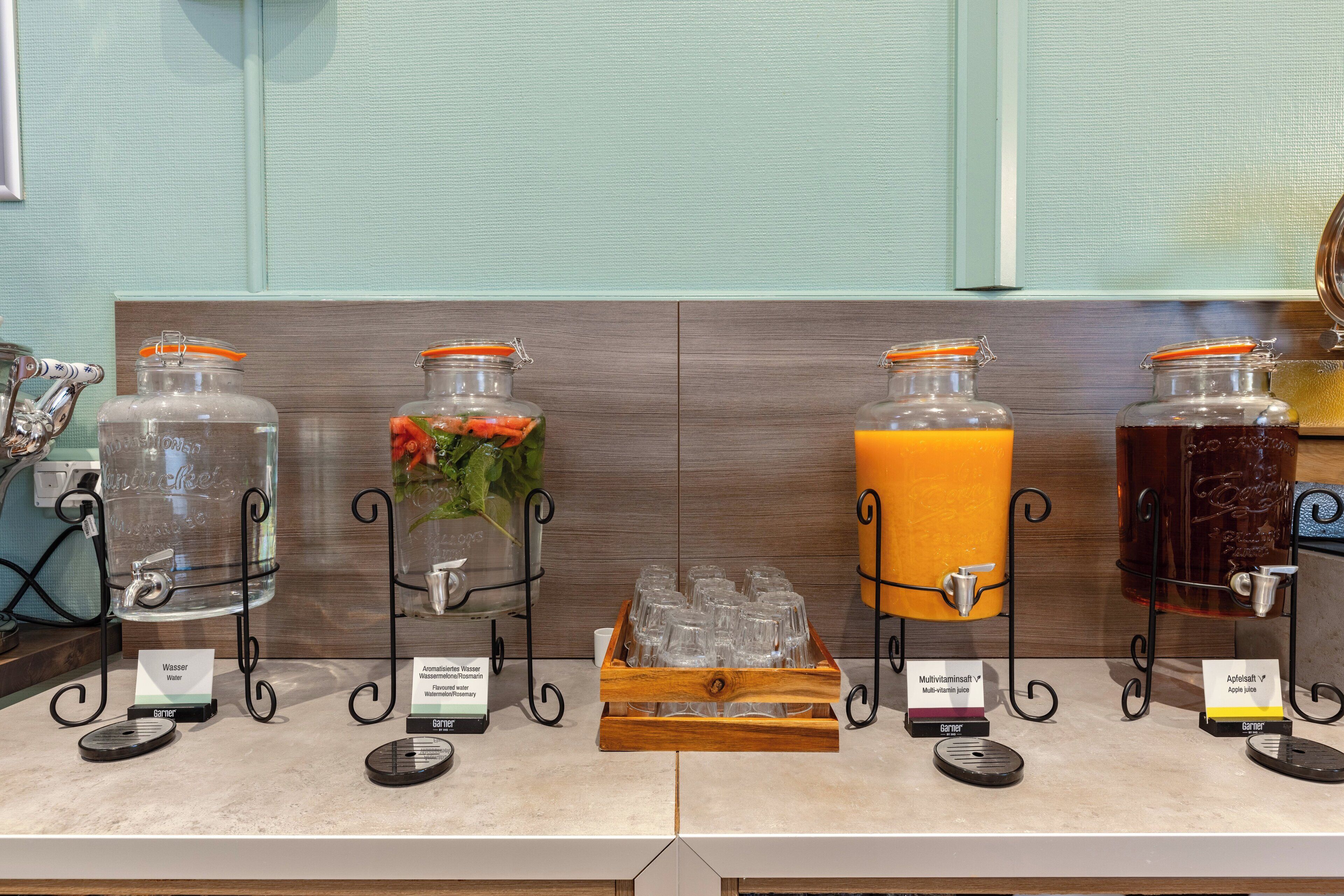 A beverage station with water, rose water, apple juice, and multivitamin juice dispensers.