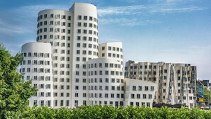 A modern building with multiple cylindrical sections, large windows, and a mix of white and grey facades. - Garner Hotel Dusseldorf Main Station by IHG (Düsseldorf)