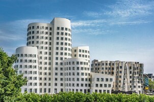 Un edificio moderno caratterizzato da sezioni cilindriche, ampie finestre e un mix di facciate bianche e grigie.