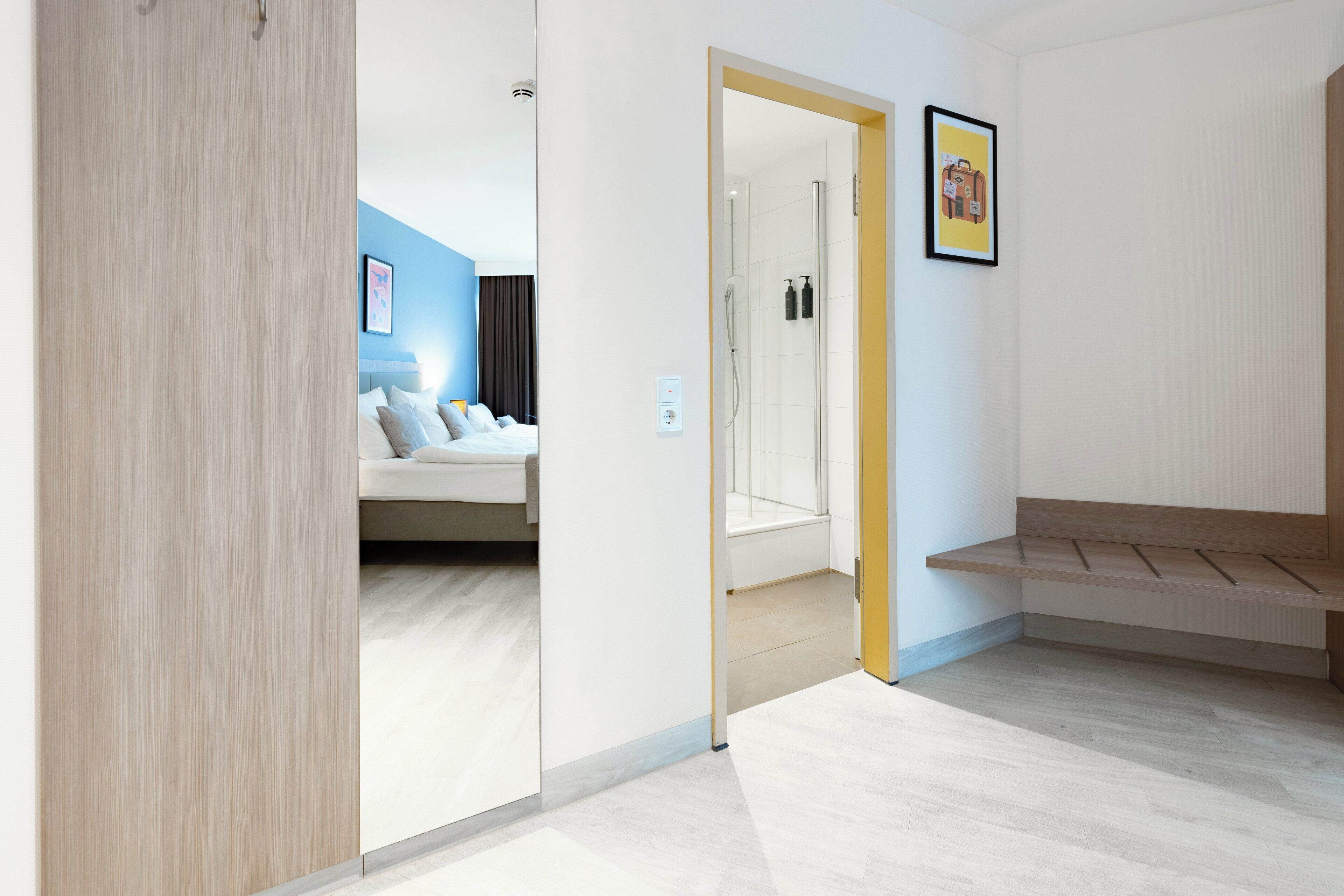 Une chambre d’hôtel moderne équipée d’un lit, d’une douche et d’un banc.