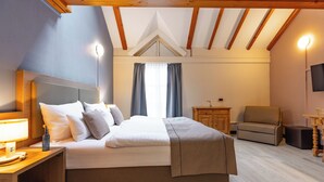 A bedroom with a bed, bedside table, lamp, and a TV on the wall. - Garner Hotel Dusseldorf Main Station by IHG (Düsseldorf)