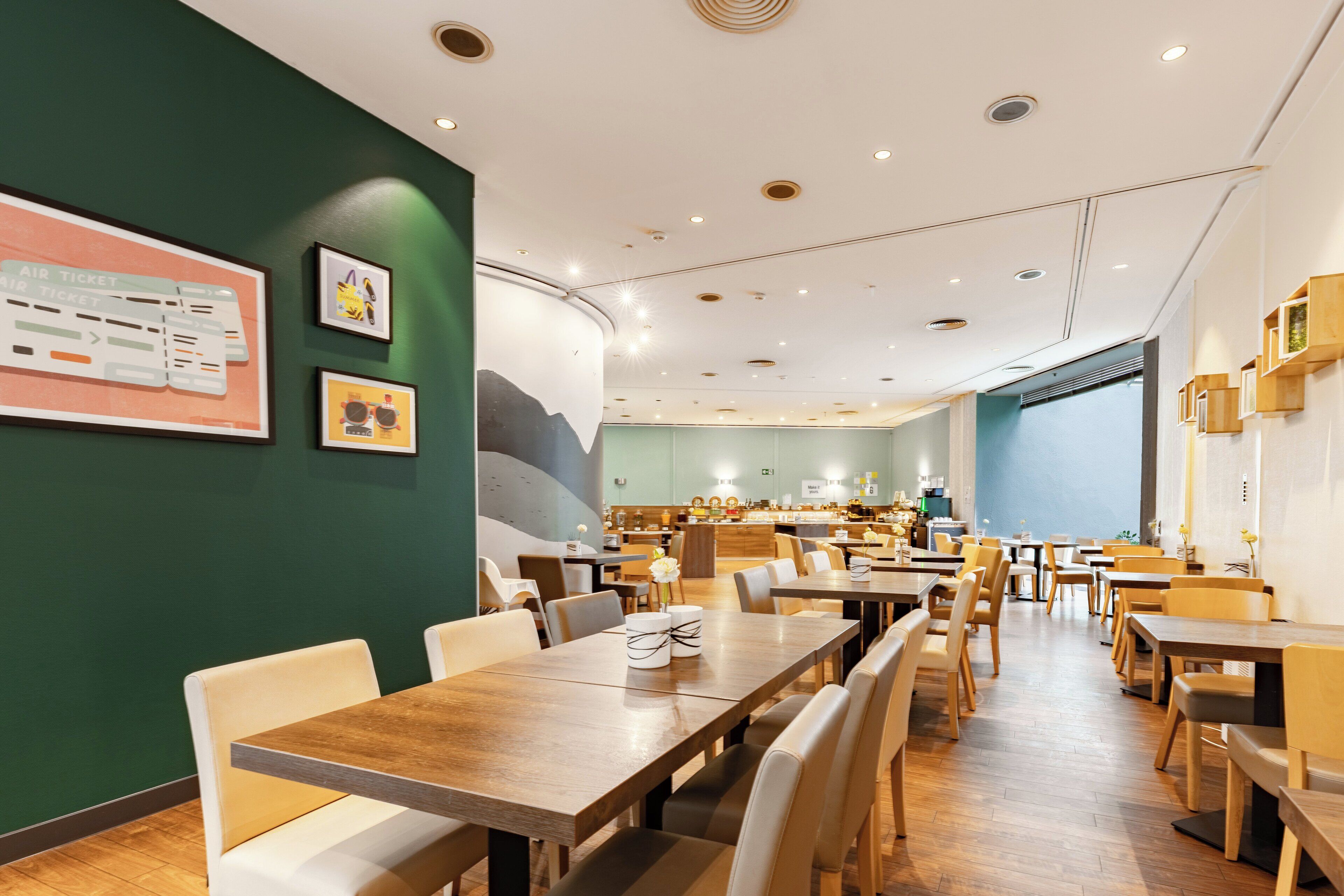 A spacious restaurant with wooden tables and chairs, a counter with a menu, and framed pictures on the walls.