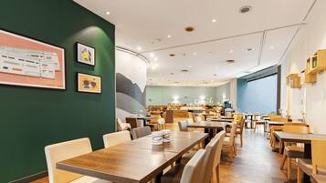 A spacious restaurant with wooden tables and chairs, a counter with a menu, and framed pictures on the walls.