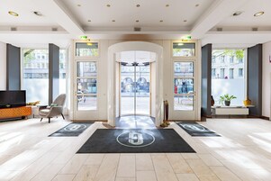 Hall d'hotel dal design moderno, con reception, area salotto e ampie finestre vista strada.