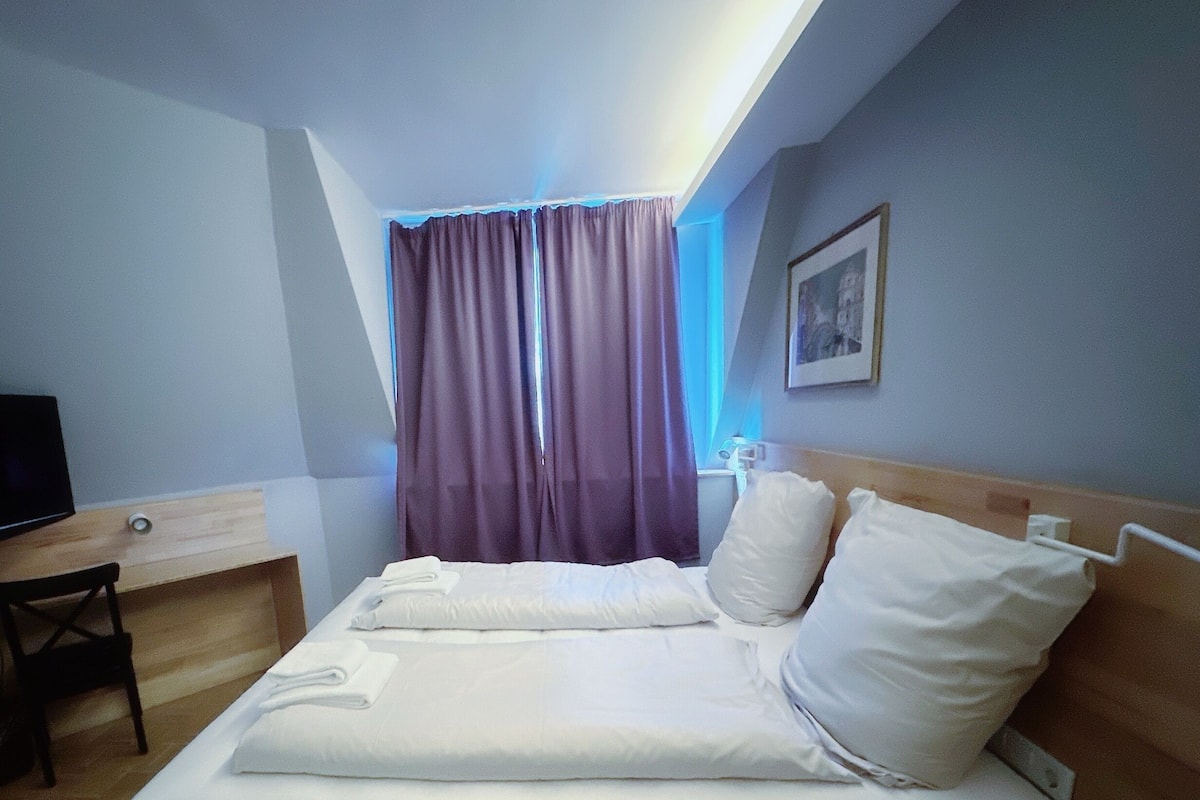 Una habitación de hotel con cama, escritorio, silla y televisor.